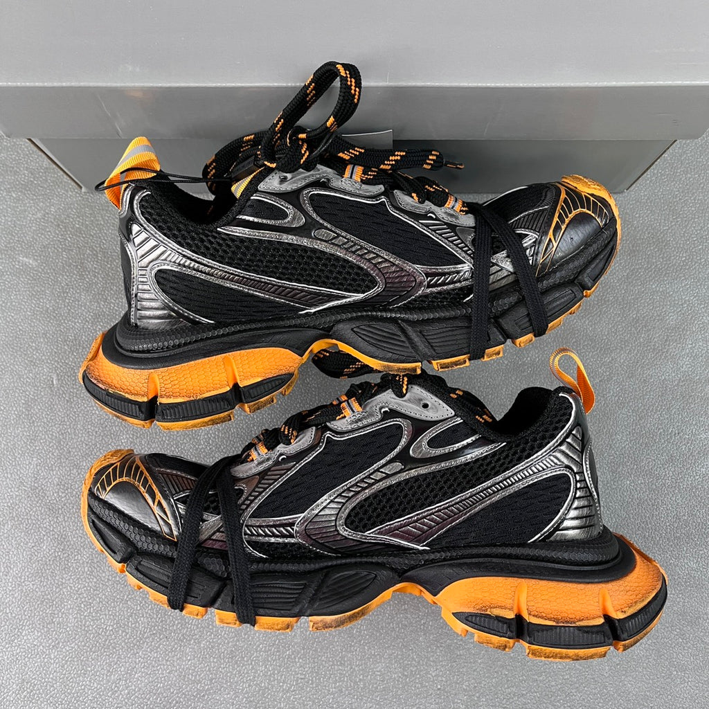 Balenciaga unisex chunky sneakers, angled pair view with black mesh, silver panels, orange soles