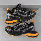 Balenciaga unisex chunky sneakers, angled pair view with black mesh, silver panels, orange soles