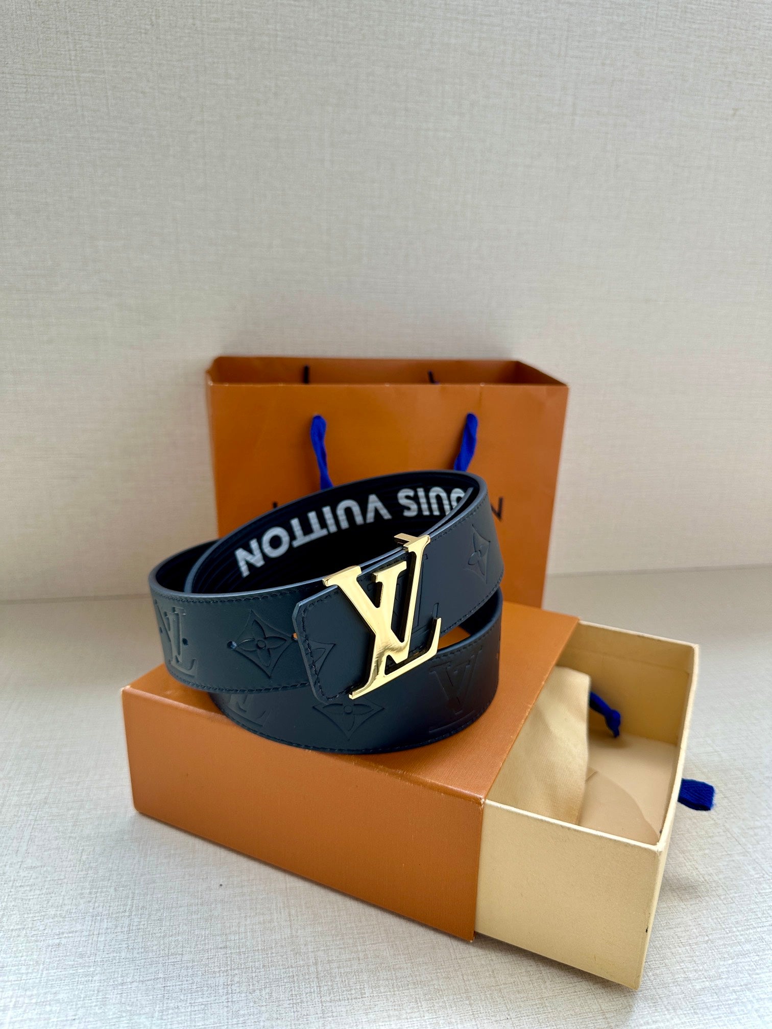 Louis Vuitton belt in dark blue with embossed monogram and prominent gold-tone buckle.