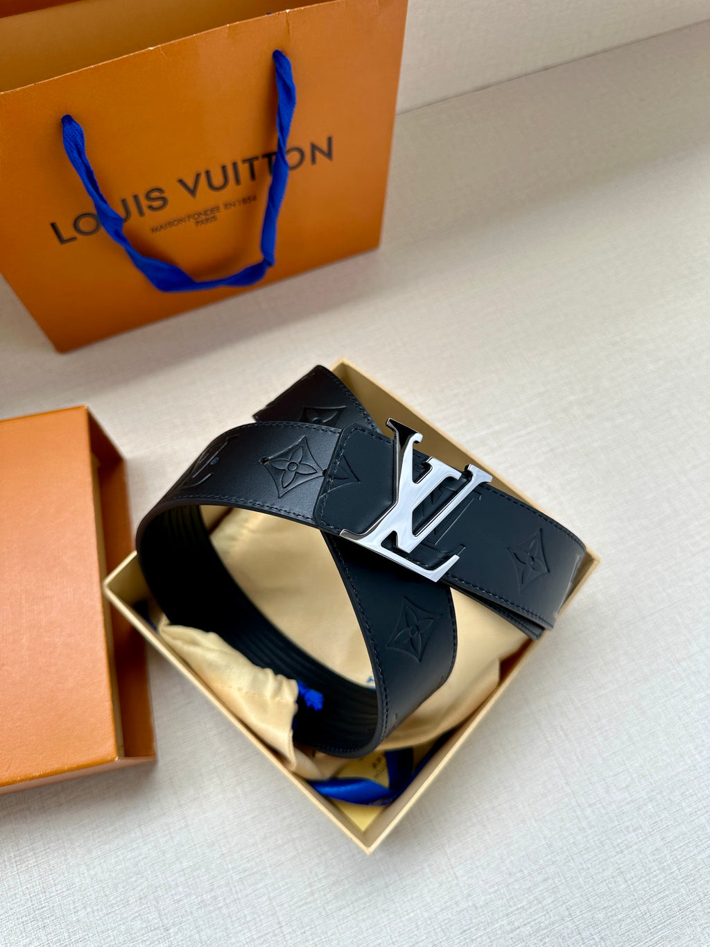 Louis Vuitton belt in dark blue with embossed monogram and shiny silver-toned buckle hardware.