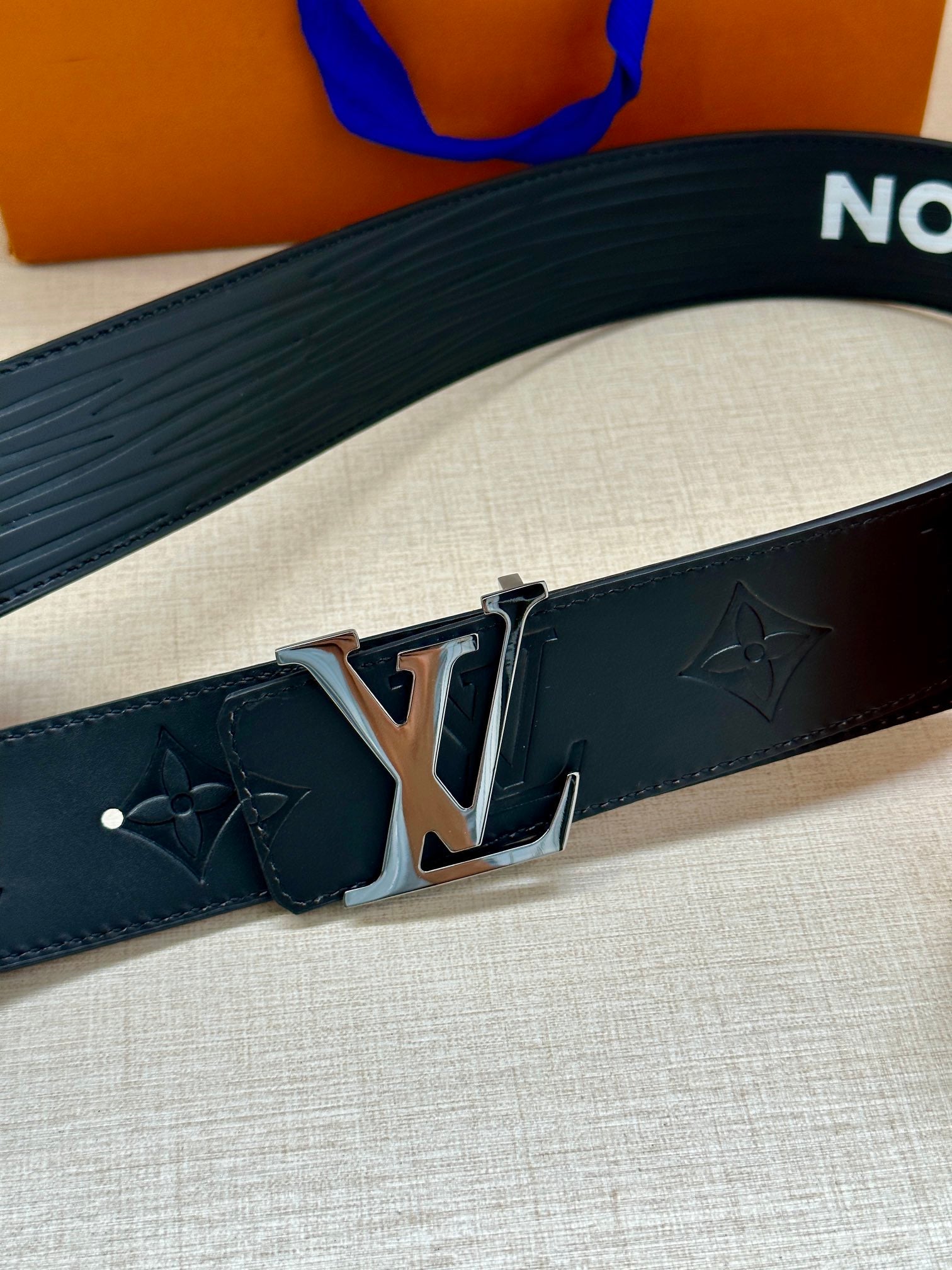 Louis Vuitton belt close-up: dark blue textured band with gold-tone buckle and clasp.