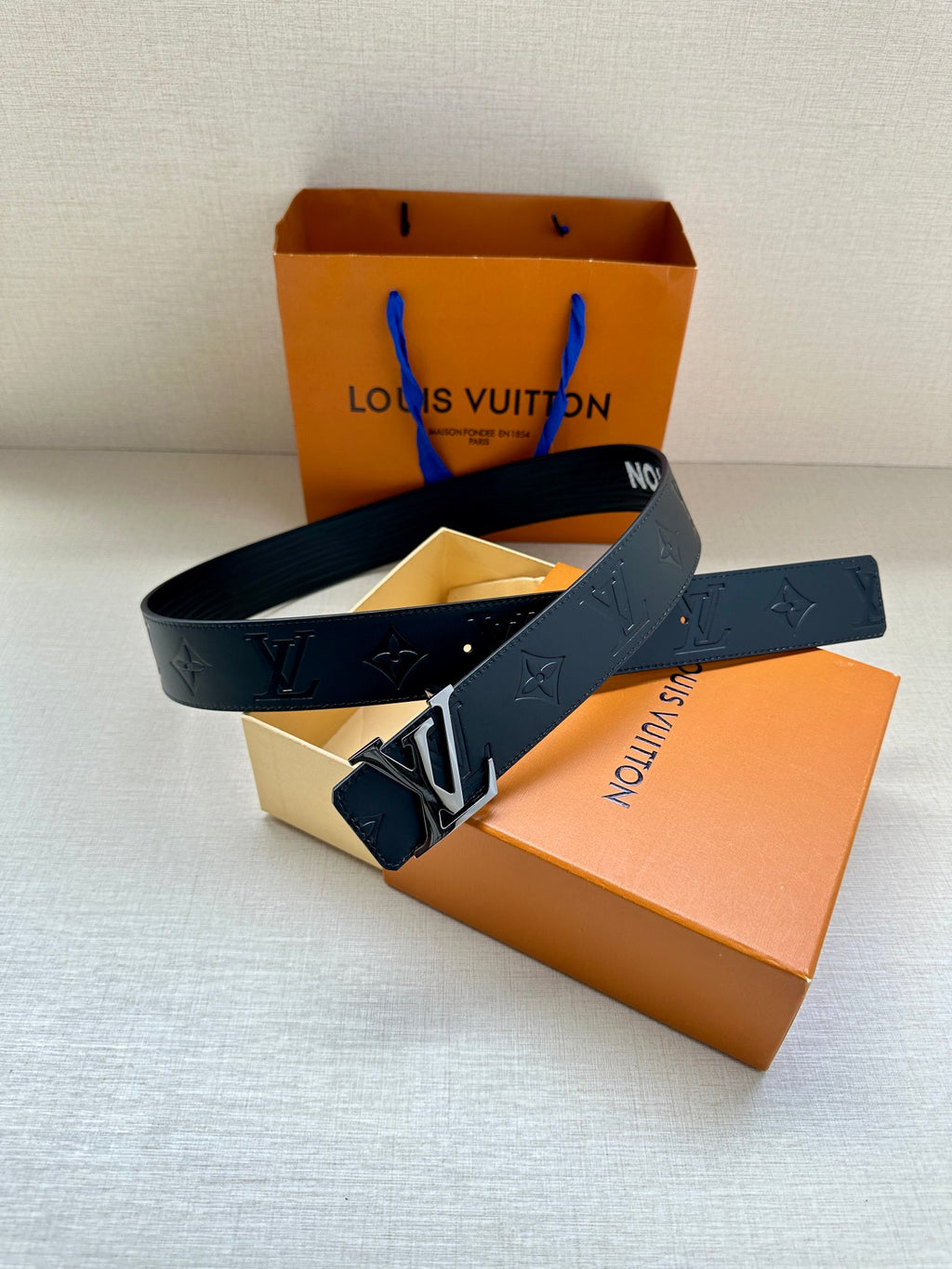 Louis Vuitton belt in dark blue with embossed monogram, gold-tone buckle, and blue loop tag.