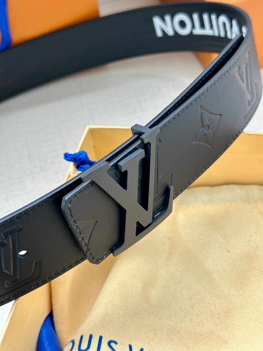 Dark gray leather belt with silver-tone buckle and embossed monogram detail