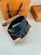 Dark gray leather belt with embossed monogram and wide silver-tone buckle, top view
