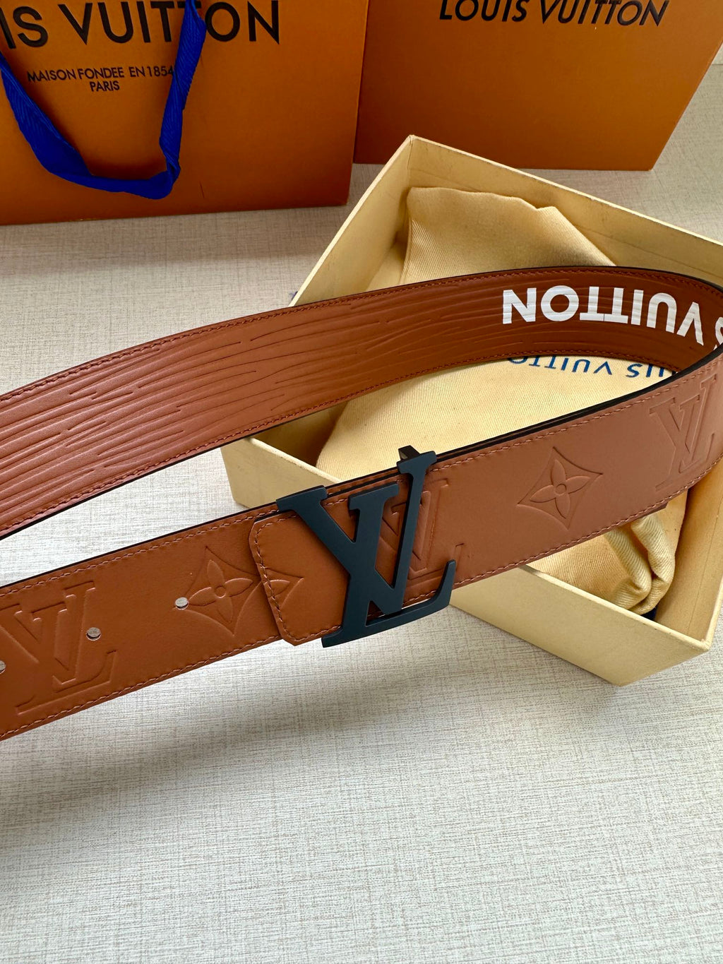 Monogram leather belt close-up with embossed pattern and dark LV buckle
