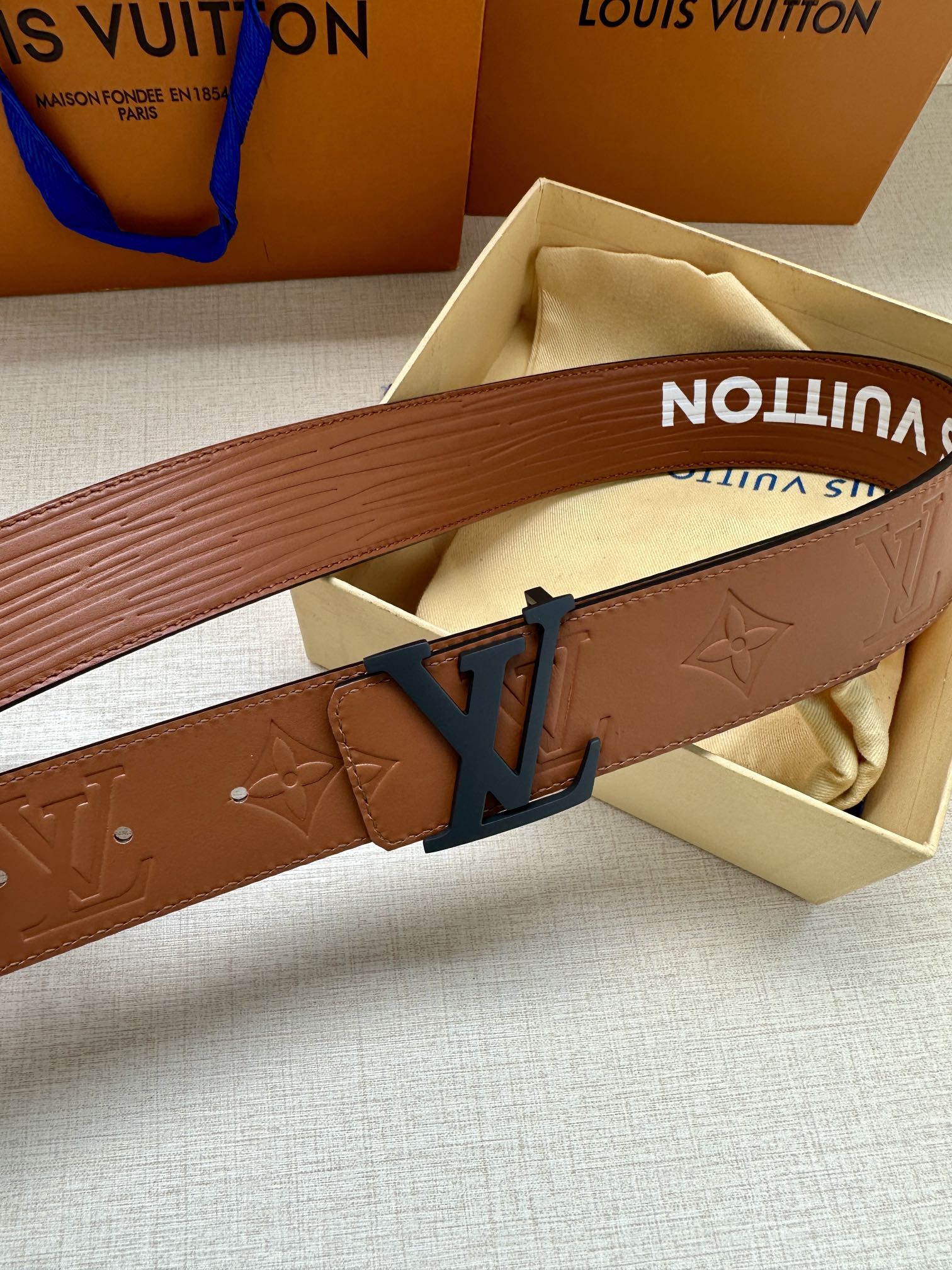 Monogram leather belt close-up with embossed pattern and dark LV buckle