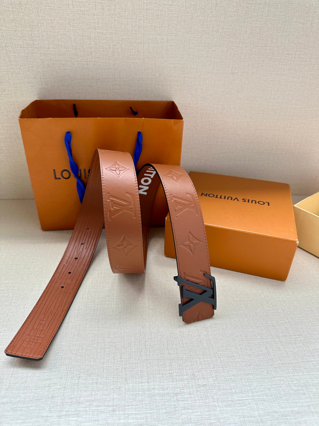 Monogram leather belt with large dark LV buckle, boxes, and strap length