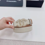 Beige leather belt held up, showing ornate gold-tone buckle with jeweled centerpiece.