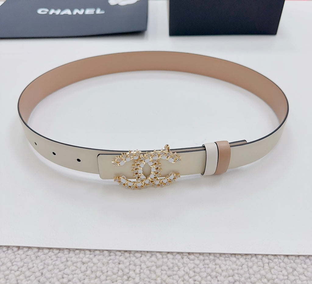 Beige leather belt coiled, with gold-tone embellished buckle and pale keeper strap.