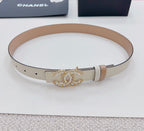 Beige leather belt coiled, with gold-tone embellished buckle and pale keeper strap.