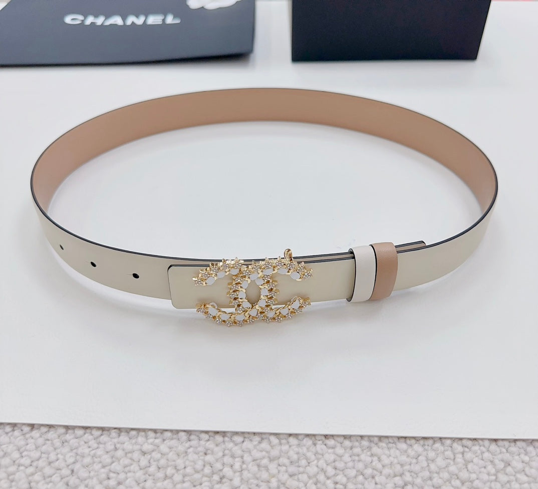 Beige leather belt coiled, with gold-tone embellished buckle and pale keeper strap.