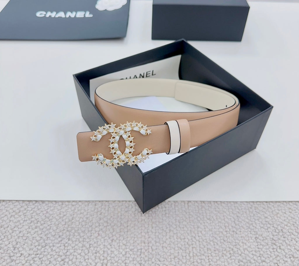 Beige leather belt with gold-tone jeweled buckle detail and light trim bands.