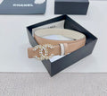 Beige leather belt with gold-tone jeweled buckle detail and light trim bands.