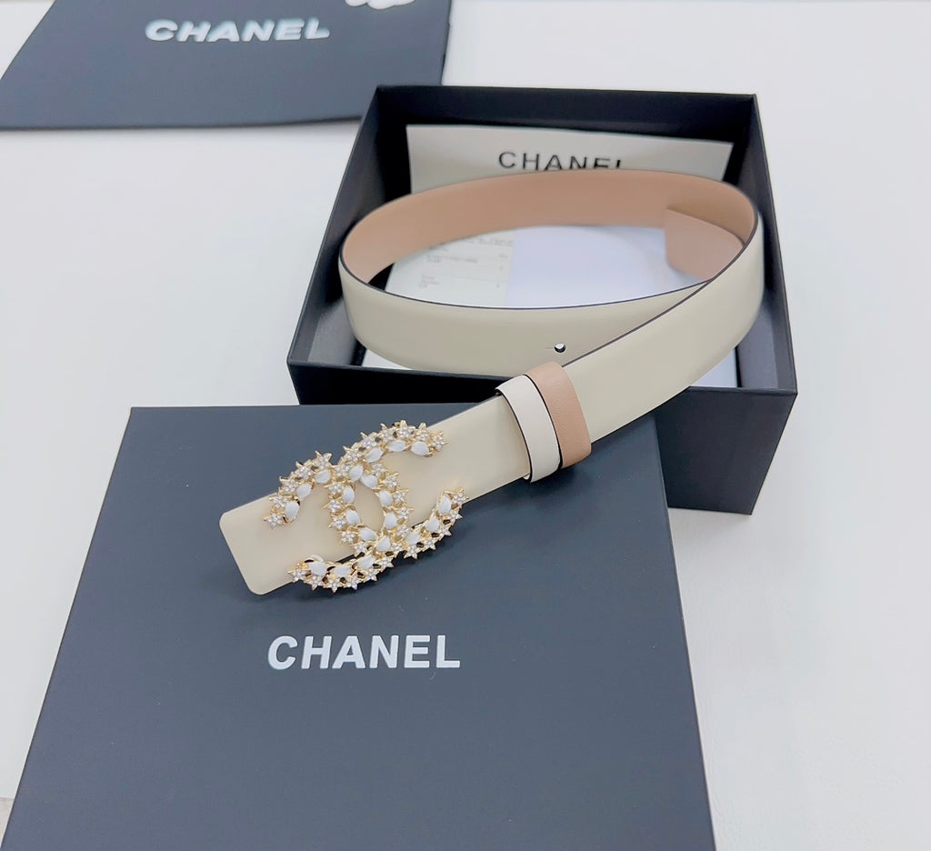 Beige belt set with a gold-tone jeweled buckle and pale double-strap keeper detail.