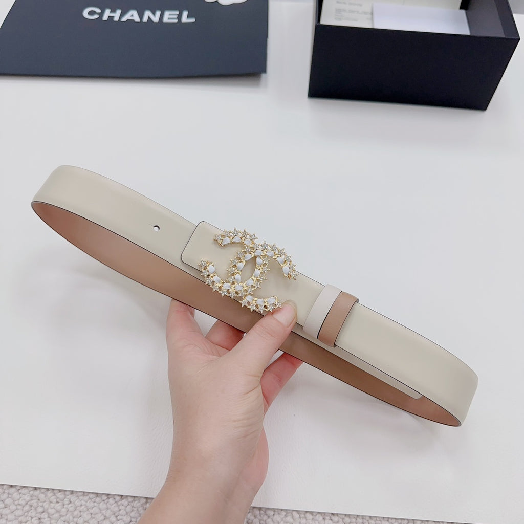 Beige leather belt with gold-tone jeweled buckle and light trim band on the strap.