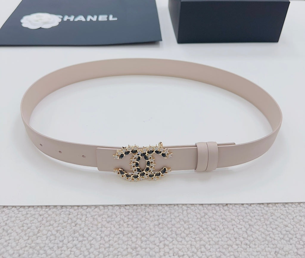 Chanel belt light beige lying flat, gold buckle with black stone logo detail.