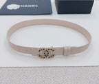 Chanel belt light beige lying flat, gold buckle with black stone logo detail.