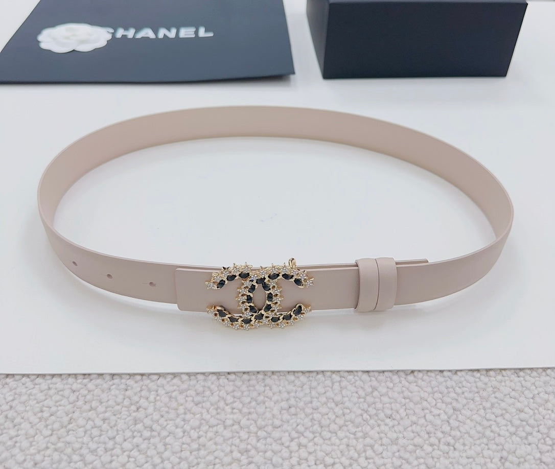 Chanel belt light beige lying flat, gold buckle with black stone logo detail.