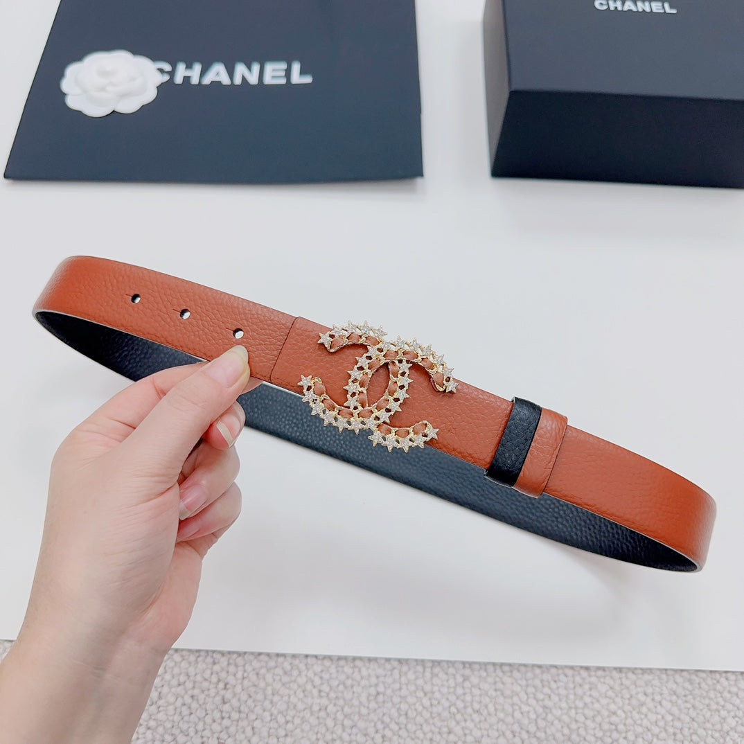 Orange and dark leather belt with decorative floral buckle shown held in hand