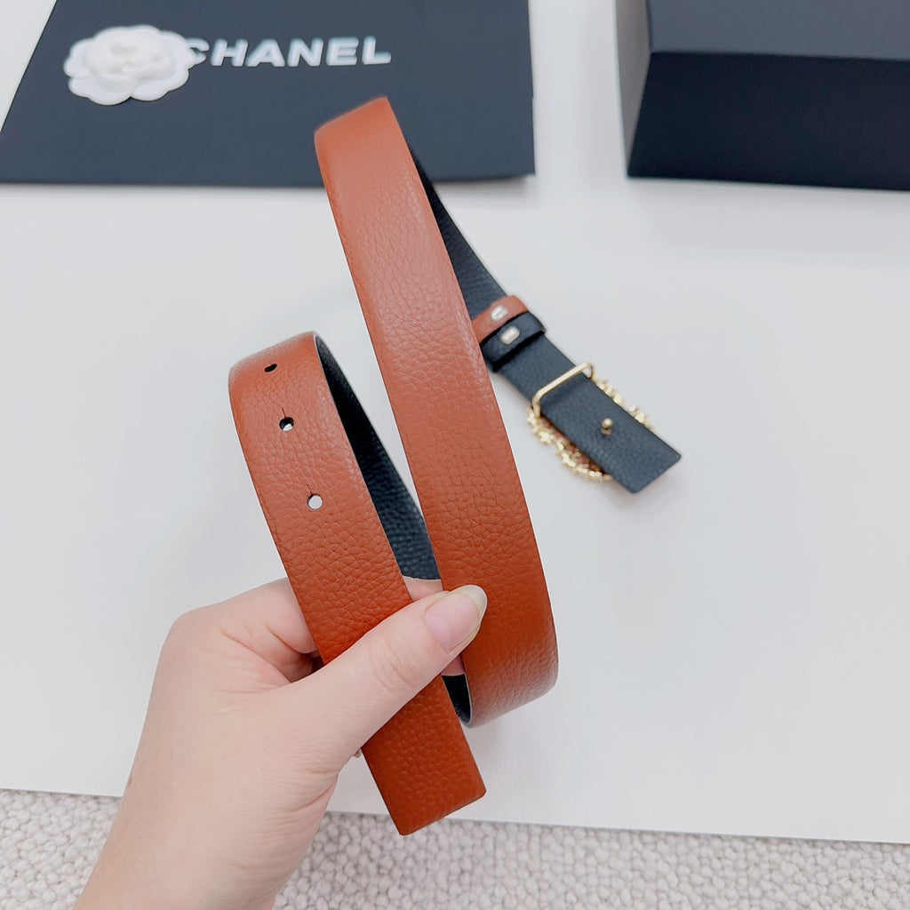 Orange leather belt with dark clasp hardware and ornate floral buckle detail