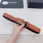Orange leather belt with decorative floral buckle and dark trim, held horizontally