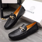 Pair of black Versace leather loafers with gold-tone buckle and embossed circular seal