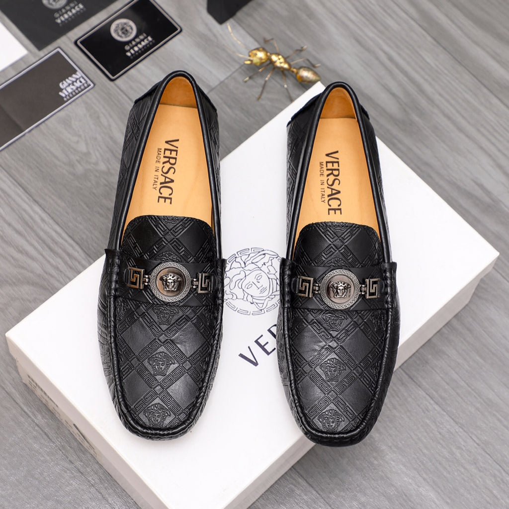 Black patterned leather loafers with gold buckle medallion and logo strap detail