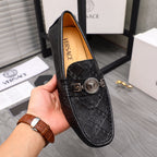 Black leather loafer with embossed pattern and gold buckle medallion at vamp