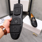 Bottom view of black loafer outsole with embossed Versace-style pattern