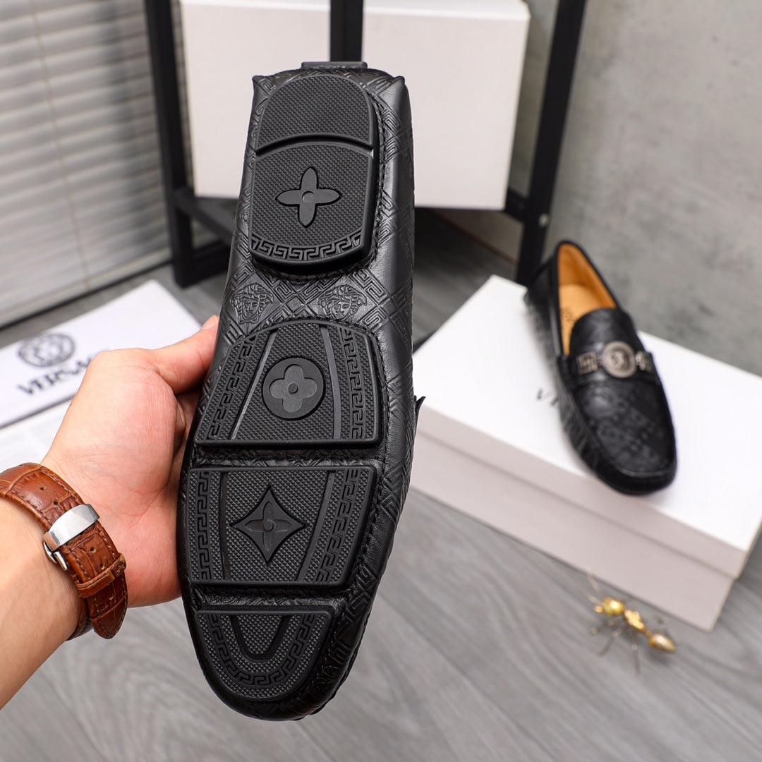 Bottom view of black loafer outsole with embossed Versace-style pattern