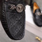 Close-up of black embossed leather loafer with gold buckle and medallion emblem