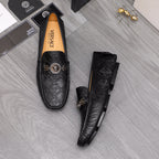 Black leather loafers with gold buckle logo strap and tan interior lining
