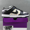 Black and white low-top sneakers with gold star print and black Nike Swoosh