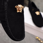Close-up of black loafer vamp with gold Medusa emblem and visible stitching