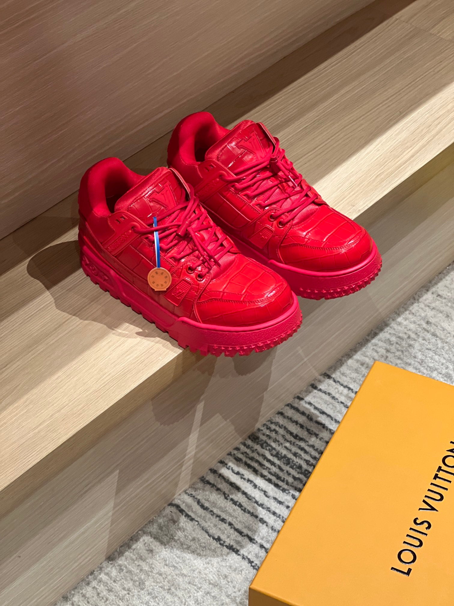 Pair of Louis Vuitton red trainer sneakers with lace-up design and treaded rubber sole