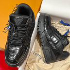 Black Louis Vuitton trainer sneakers in a box, angled side views.