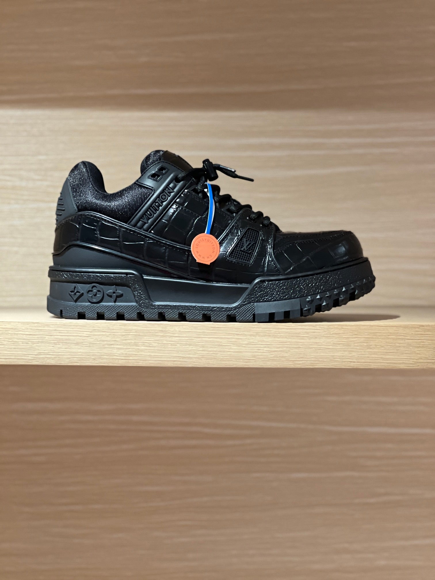 Black low-top trainer sneakers with textured panels and lace-up closure.