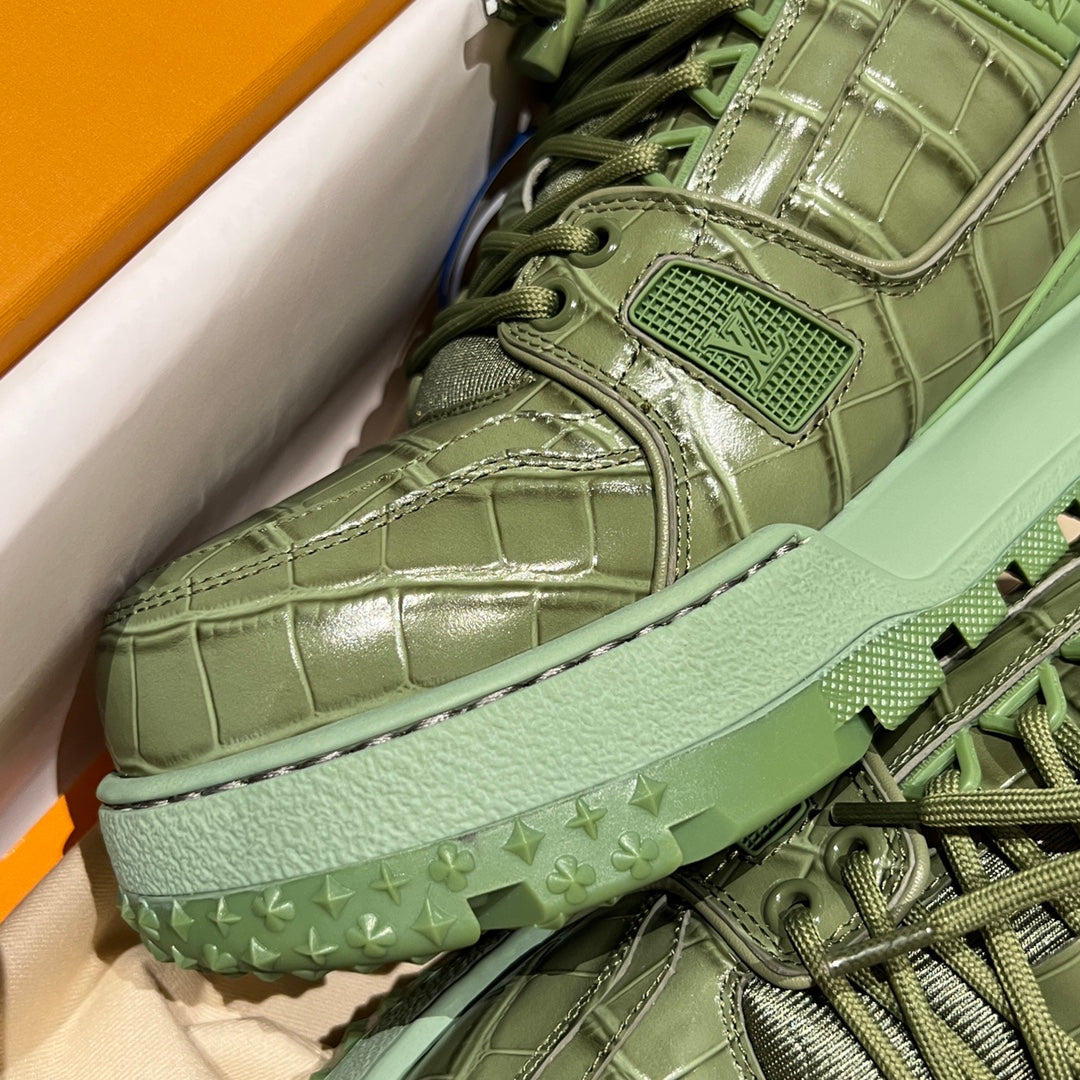 Green leather trainer close-up showing lace eyelets, stitched panels and logo patch