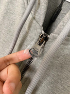 Zip-up hoodie zipper detail with metal pull and hood drawcord ends on heather gray