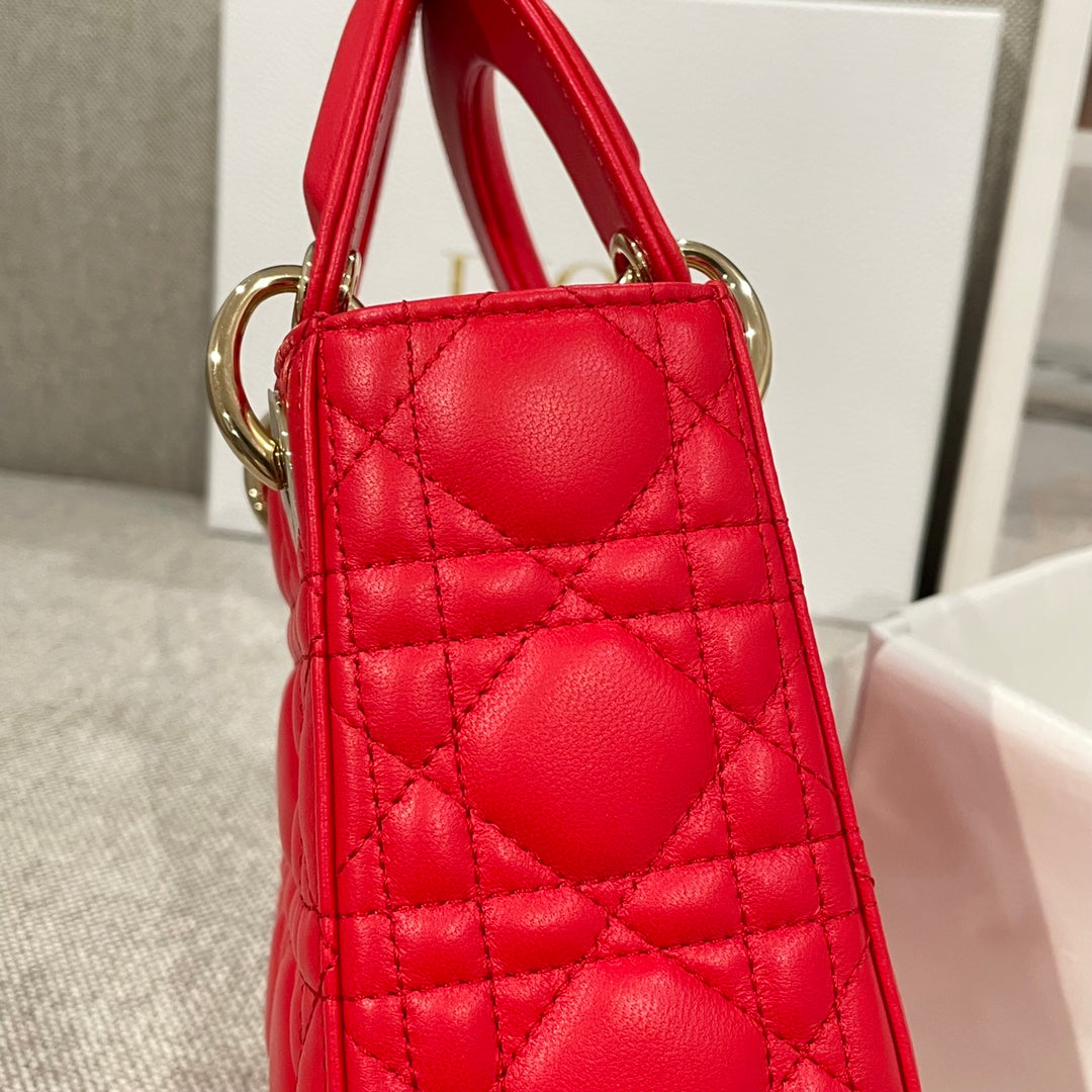 Red quilted Dior handbag side view with top handles and gold rings