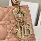 Dior mini handbag charm close-up with Dior logo on round tag and gold hardware