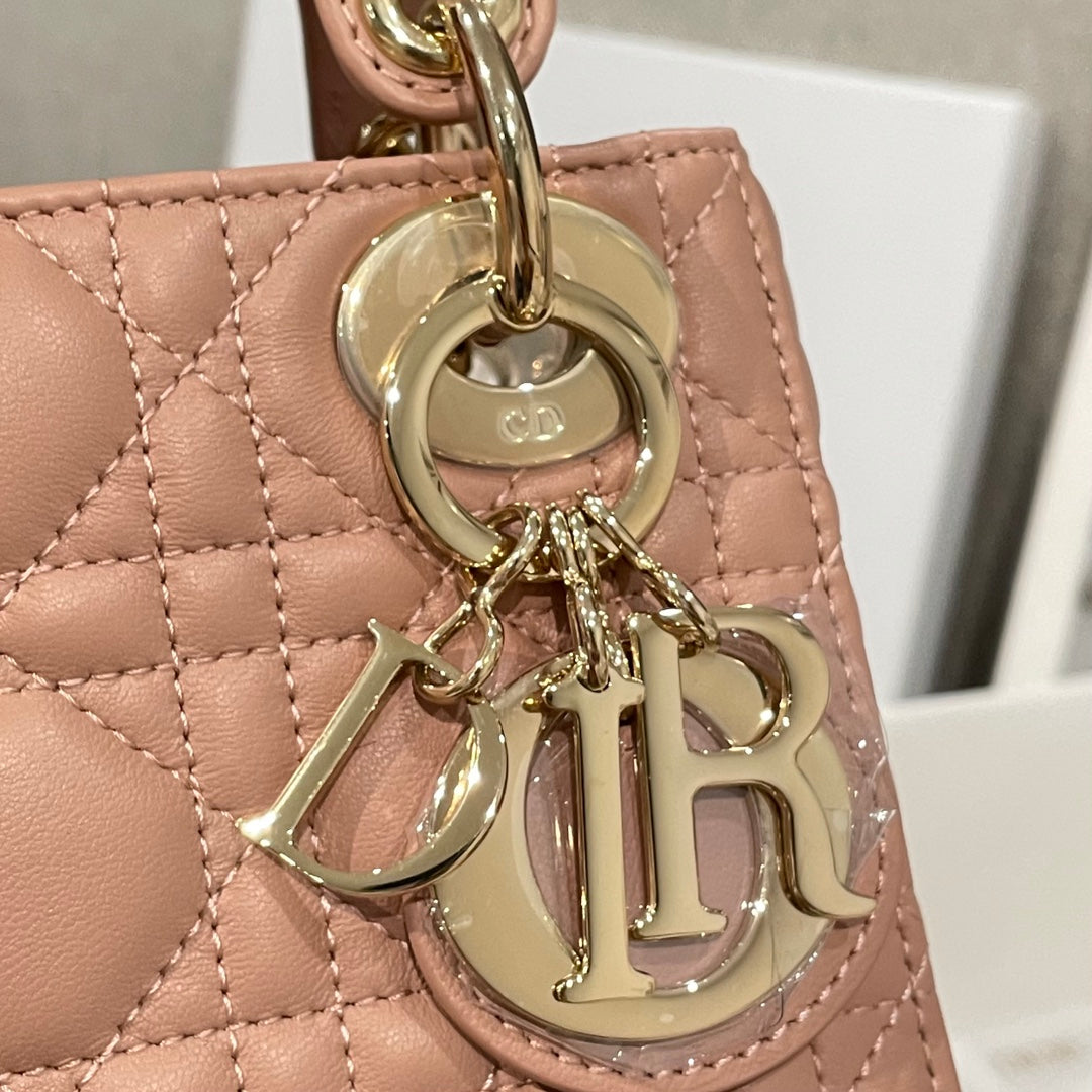 Dior mini handbag charm close-up with Dior logo on round tag and gold hardware