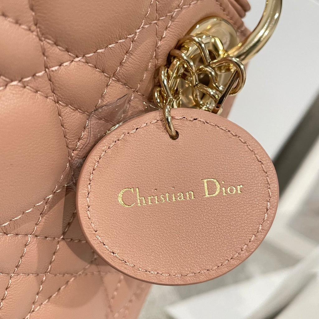 Dior mini handbag round charm labeled Christian Dior on light pink quilted leather