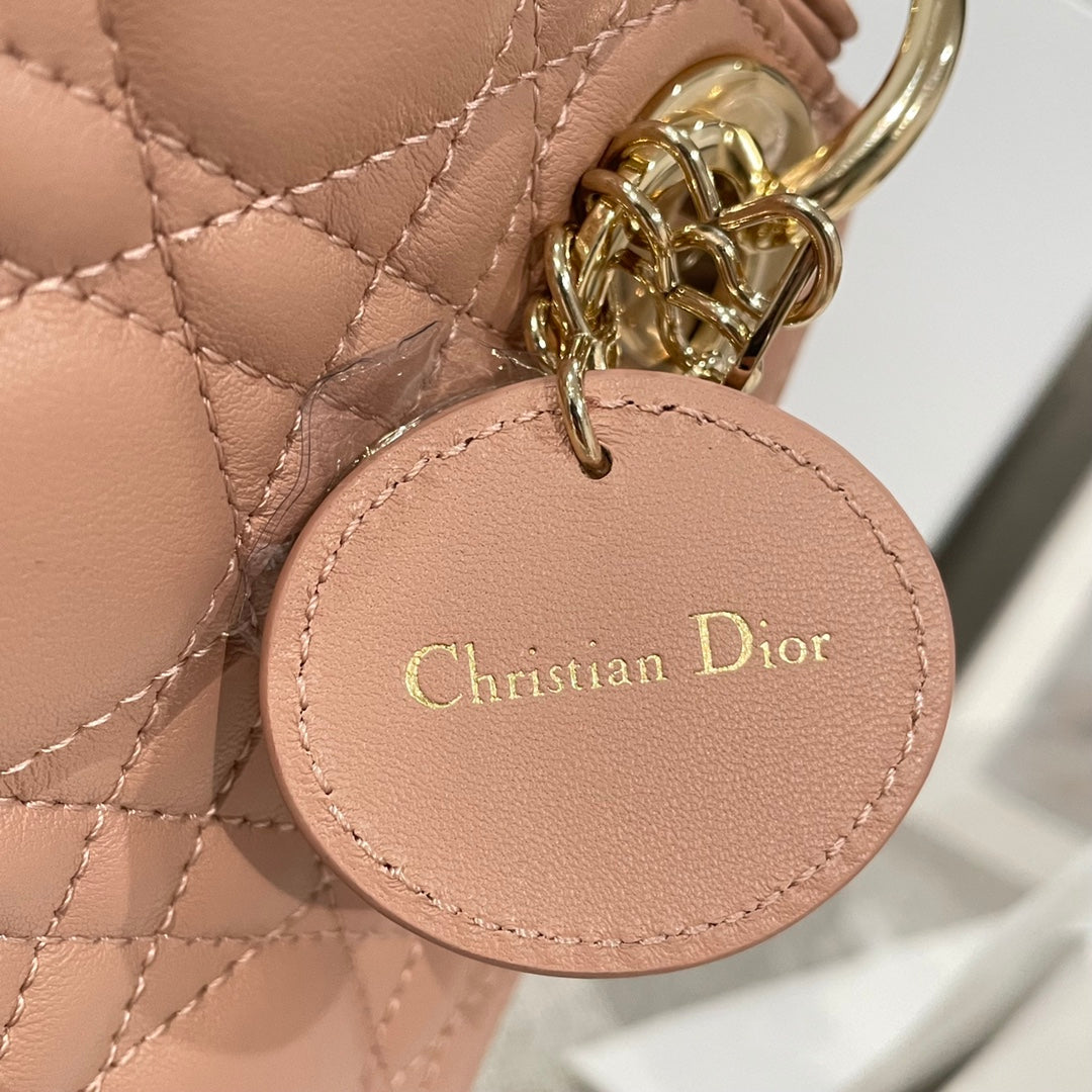 Dior mini handbag round charm labeled Christian Dior on light pink quilted leather
