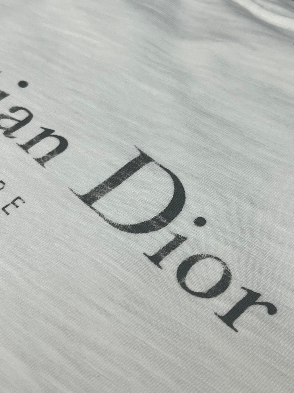 Dior short-sleeve T-shirt, close-up of large “Dior” logo print on white fabric
