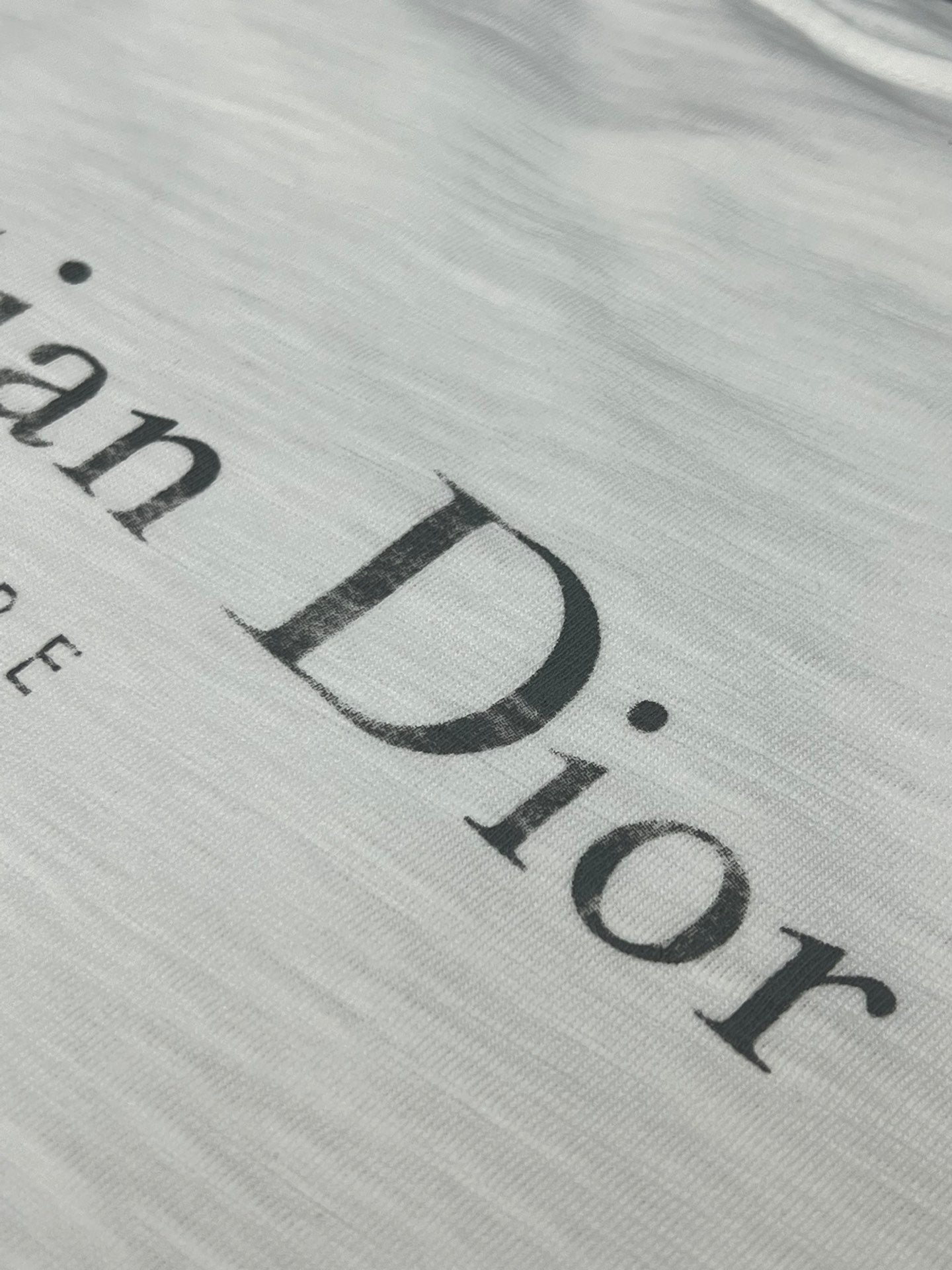 Dior short-sleeve T-shirt, close-up of large “Dior” logo print on white fabric