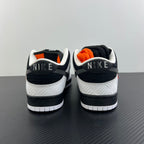 Black and white sneakers with white midsole and orange accents at the heel collar