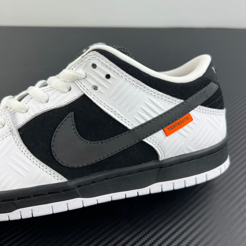 Close-up side view of black and white low-top sneaker with swoosh and orange patch