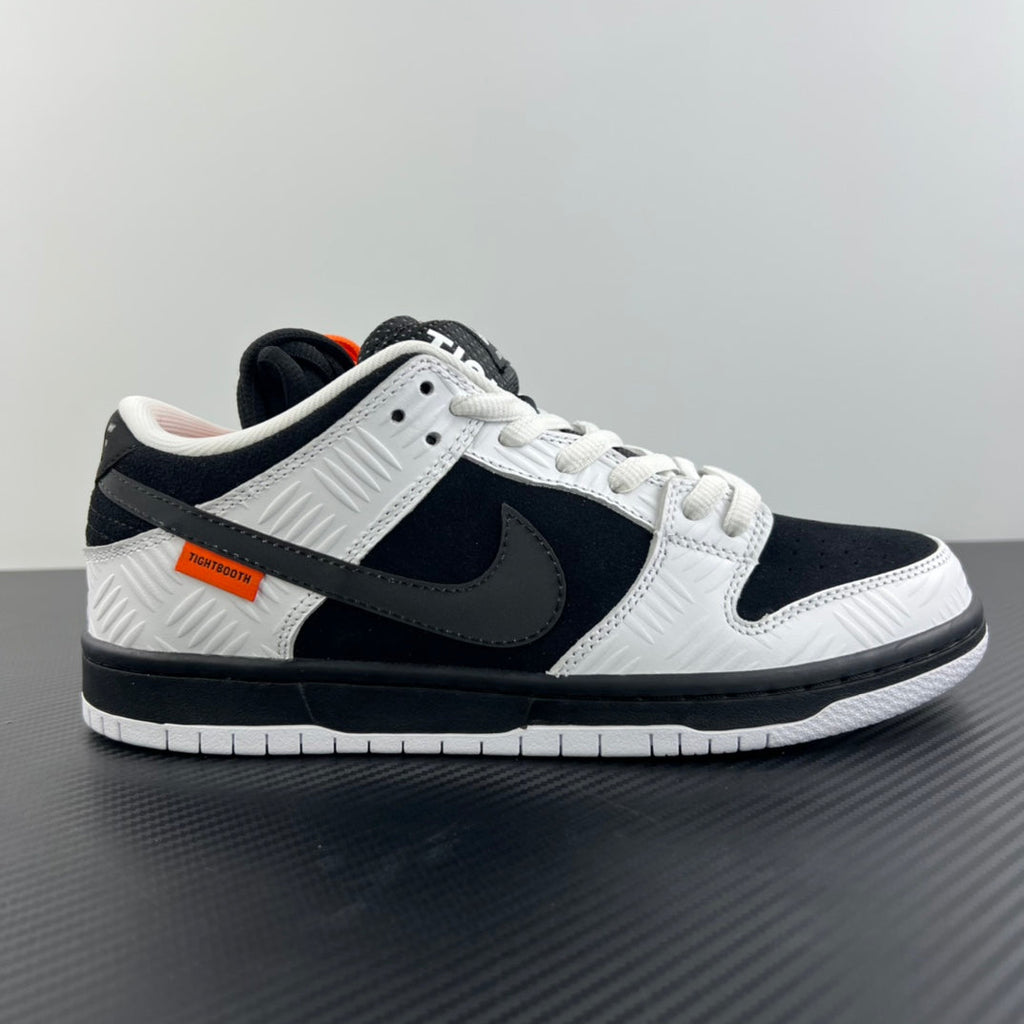 Black and white low-top sneakers, white laces, dark overlays, and orange label detail