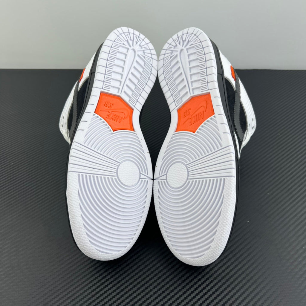 Outsole view of black and white low-top sneakers with orange forefoot traction marks